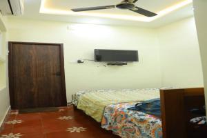 um quarto com uma cama e uma televisão de ecrã plano na parede em Heritage home with 2 bed/2 bath with kitchen in a residential neighborhood. em Madurai