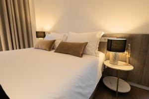 a bedroom with a white bed with two lamps on it at Watts House in Seia