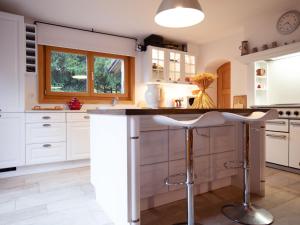 una cocina con armarios blancos y una isla con taburetes en Chalet Chalet Le Haut Pré by Interhome, en Villars-sur-Ollon