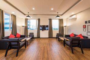 Super Townhouse MG Road,Bangalore في بانغالور: غرفة معيشة مع كنب وطاولات ونوافذ