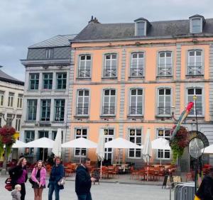 eine Gruppe von Menschen, die vor einem großen Gebäude spazieren in der Unterkunft Le Vieux Cèdre Grand Place in Mons