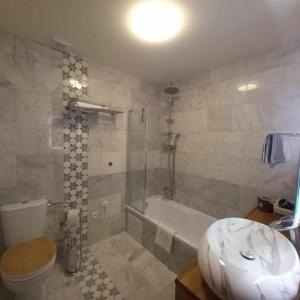 ein Badezimmer mit einer Badewanne, einem WC und einem Waschbecken in der Unterkunft Apartmány & Wellness Revenite in Jeseník