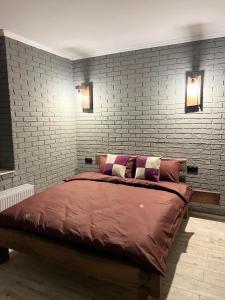 a bedroom with a large bed with a brick wall at Luxury Live in Kamianets-Podilskyi