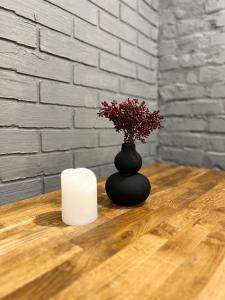 a black vase with a candle on a wooden table at Luxury Live in Kamianets-Podilskyi