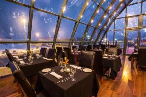 a restaurant with tables and chairs in a room with a large window at Guesthouse Keflavik by Reykjavik Keflavik Airport in Keflavík