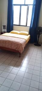 a bedroom with a bed with blue curtains and a window at Hostal Iberia in Talara