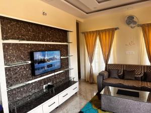 un soggiorno con divano e TV a parete di DEEYA Guest House - A Luxury Home Stay a Mysore