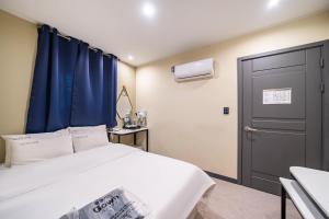 una camera con letto bianco e tenda blu di Hotel Rodem a Incheon