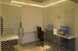 an office with a glass desk and a chair at The President Hotel in Hubli