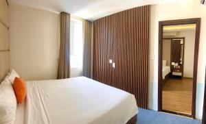 1 dormitorio con cama blanca y espejo en Pariat River Front Hotel, en Da Nang