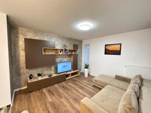 een woonkamer met een bank en een flatscreen-tv bij Deluxe Cozy Apartments - Coresi Mall #Brasov in Braşov