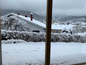 a view from a window of a house covered in snow at Charmant chalet, spacieux, proche du lac, vue sur la montagne in Gérardmer