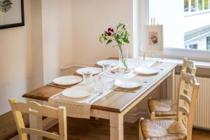 - une table à manger avec des assiettes blanches et des fleurs dans l'établissement 120qm, cozy Apartment, sehr zentral am HBF, 3SZ, à Coblence