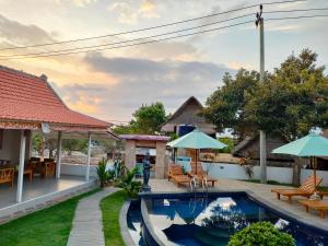 une cour avec une piscine bordée de chaises et de parasols dans l'établissement Blue Sky Villa Ceningan, à Nusa Lembongan