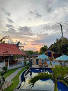 un complexe avec une piscine au coucher du soleil en arrière-plan dans l'établissement Blue Sky Villa Ceningan, à Nusa Lembongan