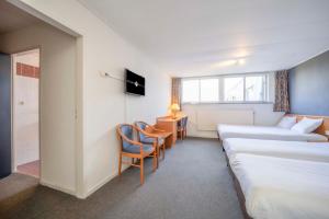 Cette chambre comprend deux lits, un bureau et des chaises. dans l'établissement Fletcher Hotel-Restaurant Waalwijk, à Waalwijk