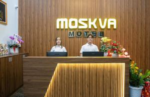 Moskva Motel & Apartment Danang في دا نانغ: يجلس شخصان في مكتب استقبال في موتيل moshiuana