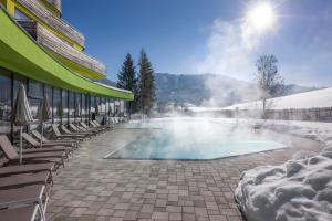 una piscina con sedie e un edificio di DAS SIEBEN - Adults Only a Bad Häring