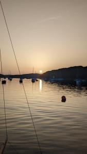 a boat in a body of water with the sunset at Modern cosy apartment walking distance to many cove beaches and coast path walks as well as the famous Helford river in Falmouth