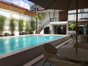 a swimming pool with chairs and a table and an umbrella at Hotel Carmelita in Tuguegarao City