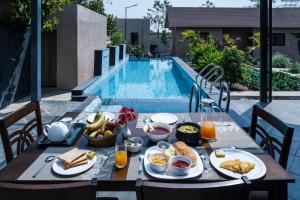 stół ze śniadaniem obok basenu w obiekcie SaffronStays Eden, Nashik - pet-friendly villa with pool, jacuzzi & grape farm w mieście Nashik