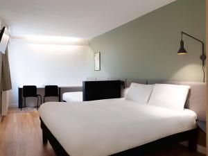 een slaapkamer met een wit bed en een tafel en stoelen bij ibis Nancy-Brabois in Vandoeuvre-lès-Nancy