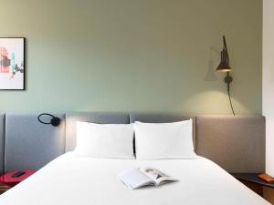 een slaapkamer met een bed met een boek erop bij ibis Nancy-Brabois in Vandoeuvre-lès-Nancy