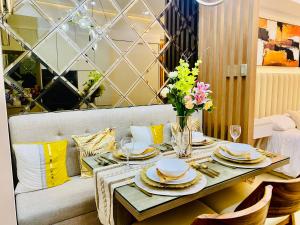 a dining room table with plates and flowers on it at Casa Arabella - Wind Residences Tower 5 2018 in Tagaytay