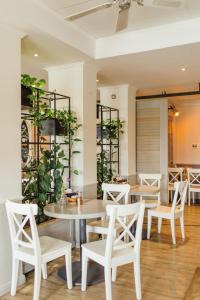 una sala da pranzo con sedie e tavoli bianchi e piante di Beach Motel St. Peter-Ording a Sankt Peter-Ording