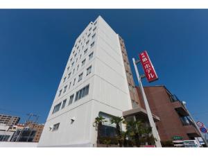 Onomichi Daiichi Hotel - Vacation STAY 02583v في أونوميتشي: مبنى أبيض طويل مع علامة أمامه