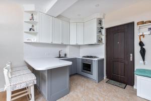 una cucina con armadi bianchi, lavandino e porta di HCG Panorama Villa Deluxe Apartment a Bakuriani