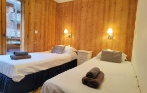 twee bedden in een kamer met houten wanden bij Slemish Apartment in Morzine