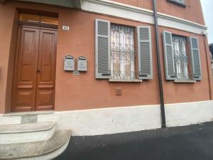 un bâtiment rose avec des fenêtres, une porte et une rue dans l'établissement MILANO 11, à Arona