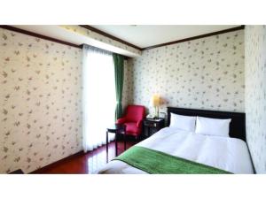 1 dormitorio con 1 cama y 1 silla roja en Old England Dogo Yamanote Hotel - Vacation STAY 75541v, en Matsuyama