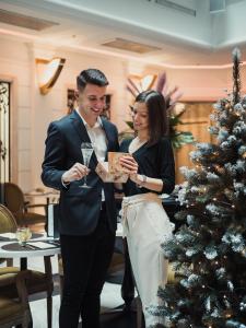 een man en een vrouw die naast een kerstboom staan bij Aria Hotel Budapest by Library Hotel Collection in Boedapest