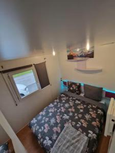 een kleine kamer met een bed en een raam bij Charmant mobilhome à 2 pas remontés ski Samoëns in Samoëns