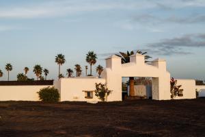 uma casa branca com palmeiras ao fundo em César Lanzarote Luxury Boutique Hotel - Adults Only em La Asomada