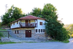 ein Haus mit einem Balkon über einer Steinmauer in der Unterkunft Melnik Pyramids Guesthouse in Zlatkov Chiflik