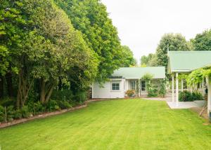 ein Haus mit einem großen Garten davor in der Unterkunft Birdsong Cottage in Paraparaumu