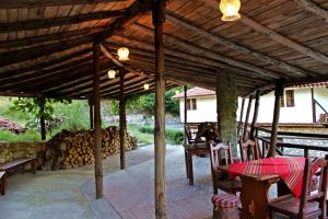 eine Terrasse mit einem Tisch und Stühlen unter einem Holzdach in der Unterkunft Melnik Pyramids Guesthouse in Zlatkov Chiflik