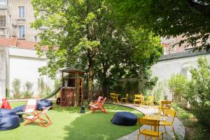 une cour avec des chaises et une aire de jeux avec un arbre dans l'établissement RockyPop Grenoble Hotel, à Grenoble