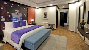 um quarto com uma cama grande e almofadas roxas em The Vibe By Ambiance em Murree