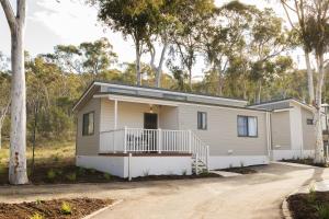 ein modulares Haus mit einer Veranda und Bäumen in der Unterkunft Alivio Tourist Park Canberra in Canberra