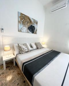 a white bedroom with a bed with black and white pillows at Pit stop Ciampino Station in Ciampino