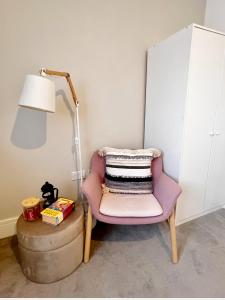 uma cadeira rosa sentada ao lado de um candeeiro e de uma mesa em Lakeside LUX bedroom with parking, M4 Jct 11, next to train station em Reading