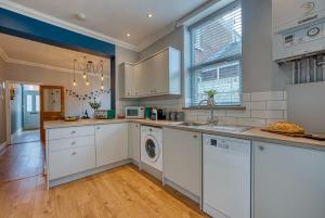 una cucina con armadi bianchi e una lavatrice/asciugatrice di XMAS SPECIAL OFFER!! 2-BR Modern, Stylish & Stunning Contractor House, Prime Portsmouth Location with Parking - By Blue Puffin Stays a Portsmouth