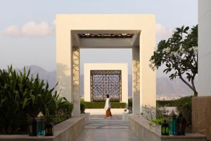 Una donna che cammina attraverso un arco in un edificio di JW Marriott Hotel Muscat a Mascate