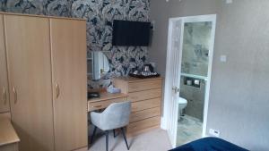 a bedroom with a desk and a dresser with a mirror at Bryn Derwen with Private Car Park in Llandudno