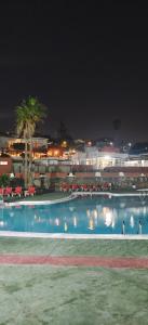 ein großer Pool mit roten Sonnenschirmen in der Nacht in der Unterkunft Relax in pasito blanco camping house in Maspalomas