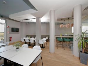 une salle à manger avec des tables et des chaises blanches dans l'établissement B&B Hotel Berlin-Airport, à Schönefeld